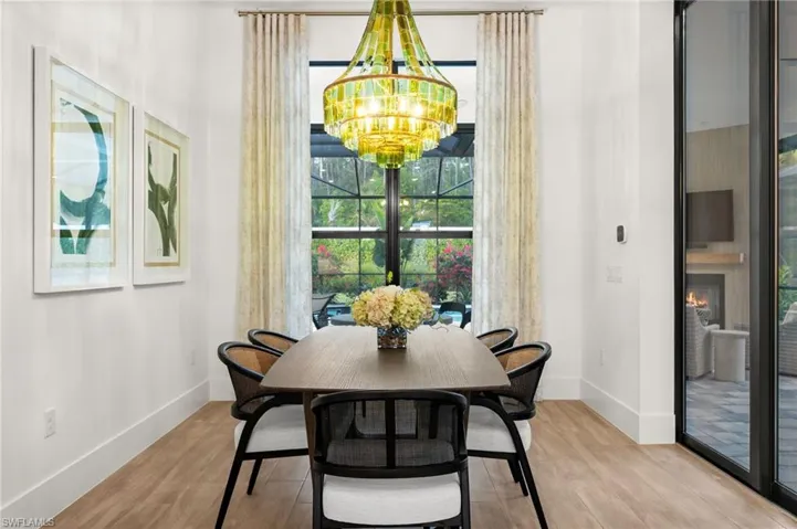 Dining room featuring wood finished floors, a chandelier, and a large fireplace