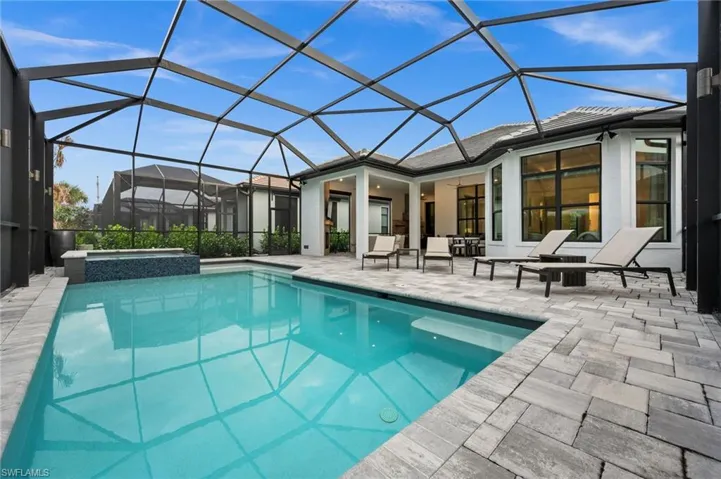 View of swimming pool with a sunroom, glass enclosure, a patio, and a pool with connected hot tub
