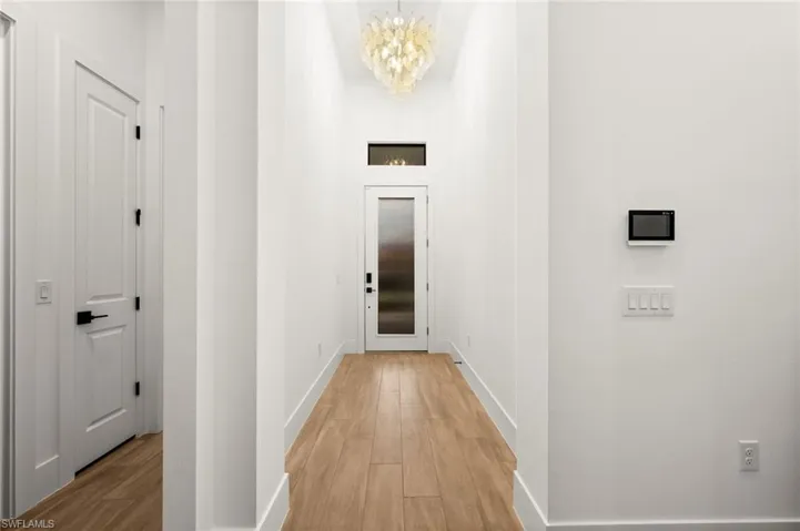 Hall featuring wood finished floors, a chandelier, and a high ceiling