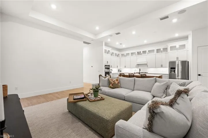 Living area featuring recessed lighting, light wood finished floors, and a tray ceiling