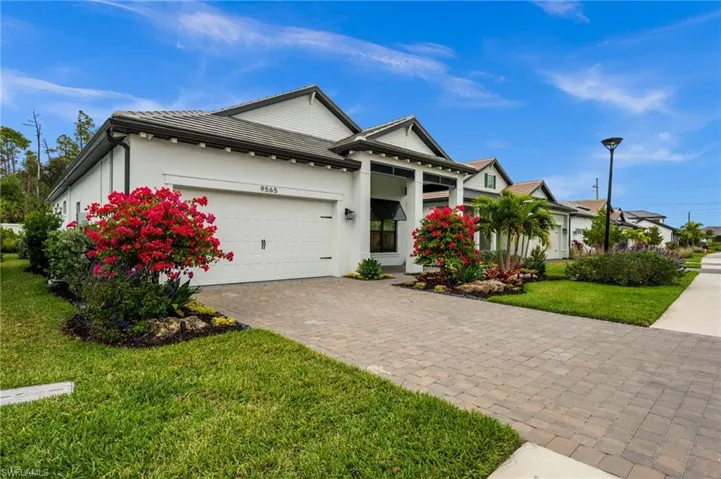 View of front of property featuring a front yard, a garage, decorative driveway, and stucco siding