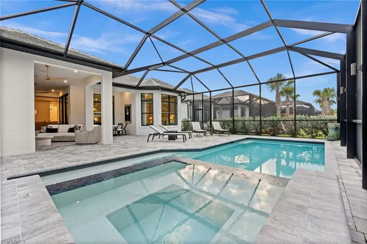 View of pool featuring a sunroom, a patio area, glass enclosure, and a pool with connected hot tub