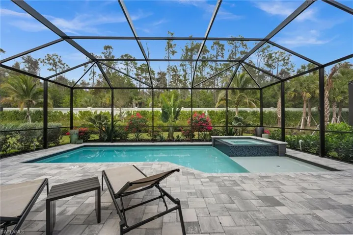 View of swimming pool featuring a sunroom, glass enclosure, a pool with connected hot tub, and a patio area