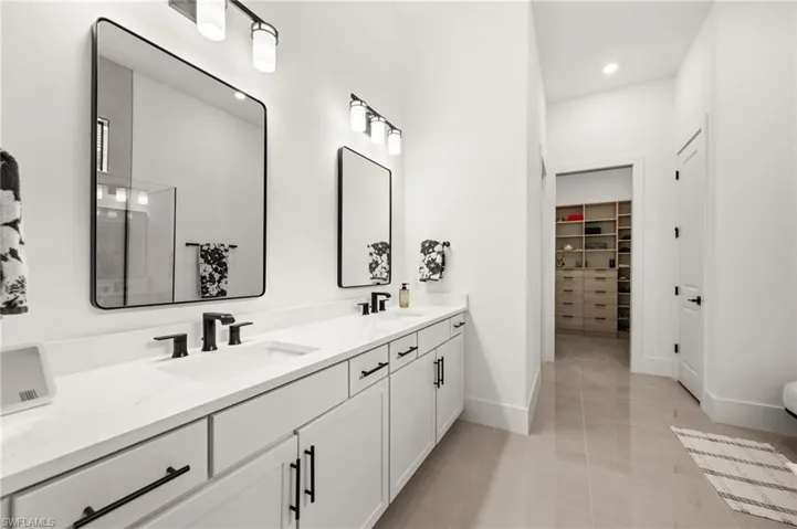 Bathroom featuring a walk in closet, double vanity, light tile patterned floors, and recessed lighting