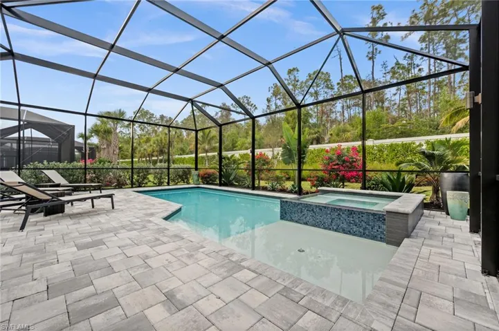 View of swimming pool with a pool with connected hot tub, a sunroom, a lanai, and a patio area