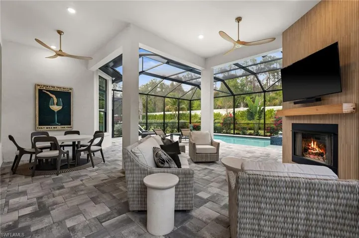 View of patio / terrace with ceiling fan, an outdoor living space with a fireplace, and glass enclosure