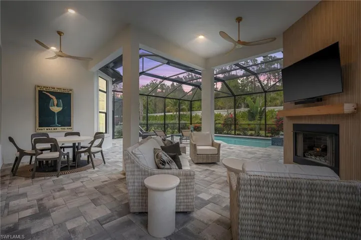View of patio / terrace featuring a ceiling fan, an outdoor living space with a fireplace, and a lanai