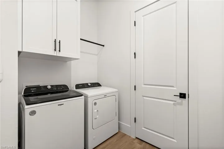 Laundry area featuring cabinet space, light wood finished floors, and washer and clothes dryer