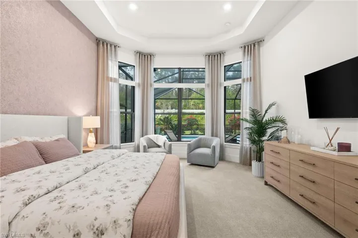 Bedroom with light carpet, a tray ceiling, and a textured wall