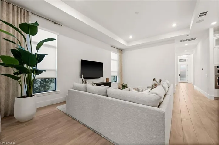 Living area with light wood-style flooring, recessed lighting, and a tray ceiling