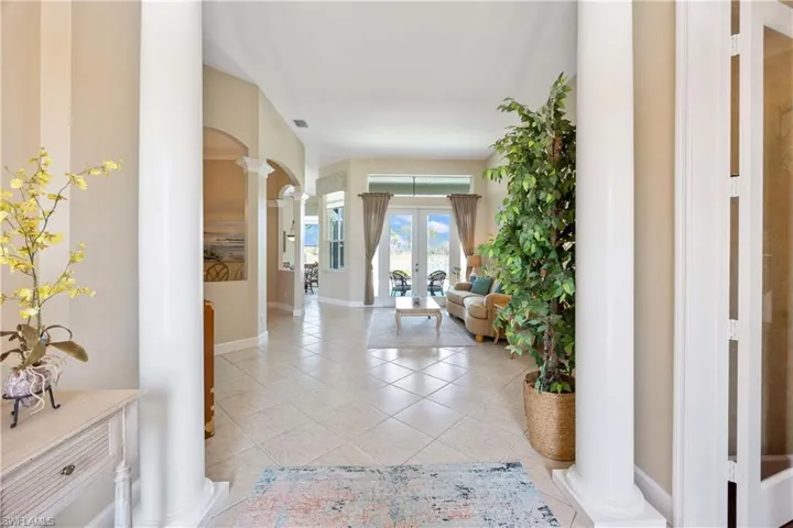 Corridor with arched walkways, light tile patterned floors, visible vents, french doors, and decorative columns