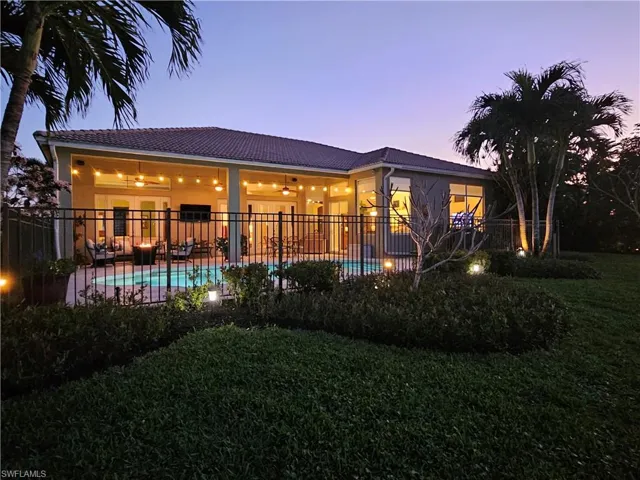 Back of house at dusk with a fenced in pool, a patio, fence, and a ceiling fan
