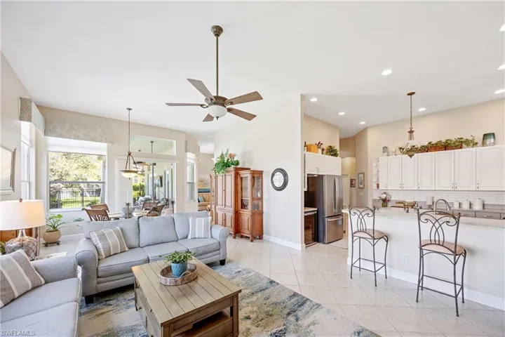 Living room featuring ceiling fan with notable chandelier, recessed lighting, baseboards, and light tile patterned floors