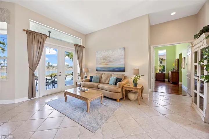 Living room with recessed lighting, baseboards, a water view, french doors, and light tile patterned flooring