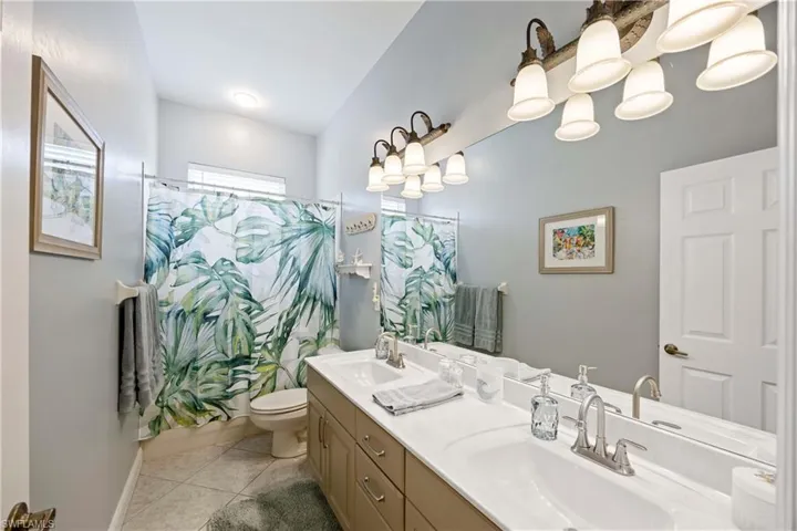 Full bath with a shower with shower curtain, tile patterned flooring, a sink, and toilet