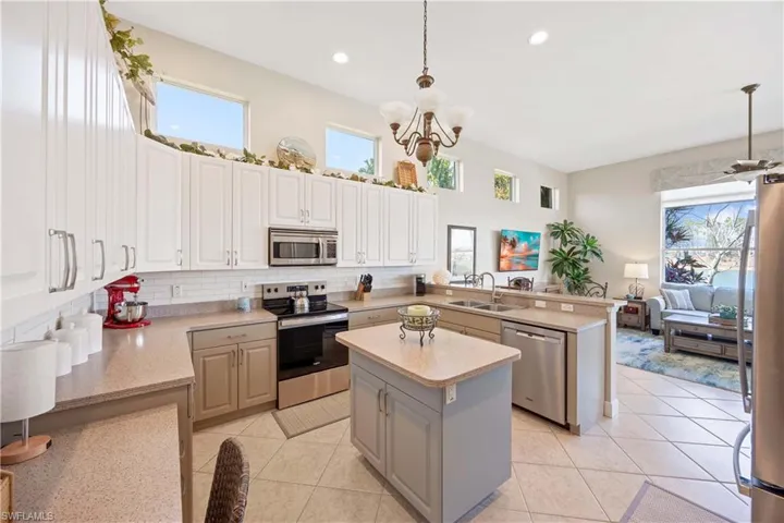 Kitchen with pendant lighting, stainless steel appliances, light countertops, a sink, and a peninsula