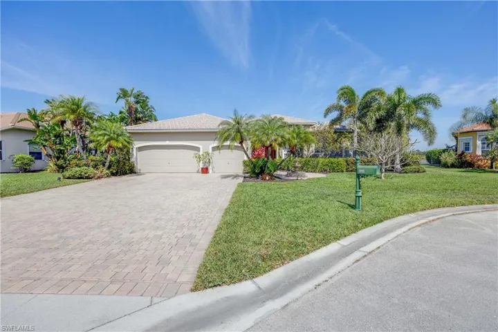 View of front facade with a garage, a tiled roof, decorative driveway, and a front yard