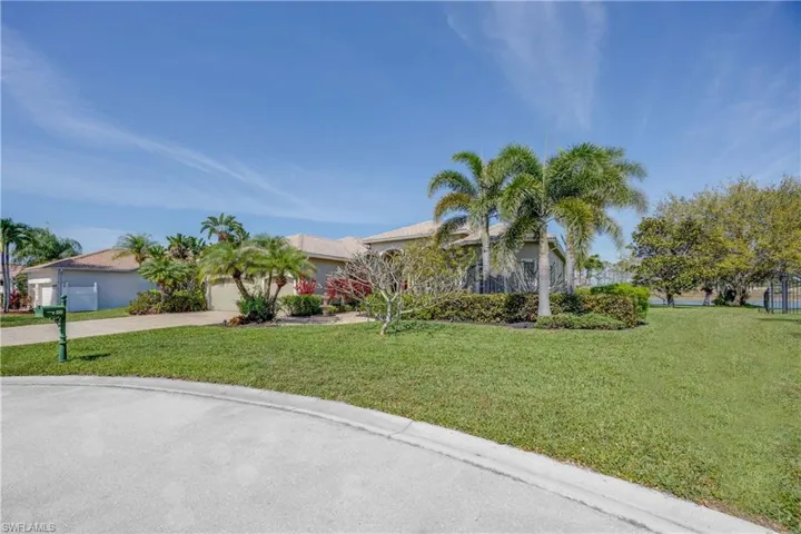 View of front facade featuring a garage, driveway, and a front yard