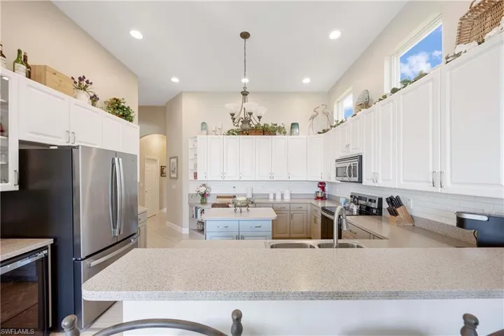Kitchen with wine cooler, white cabinetry, appliances with stainless steel finishes, glass insert cabinets, and pendant lighting