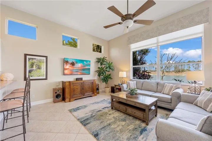 Living area with a ceiling fan, baseboards, and light tile patterned floors