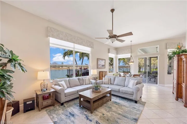 Living room featuring light tile patterned floors, a water view, and a healthy amount of sunlight