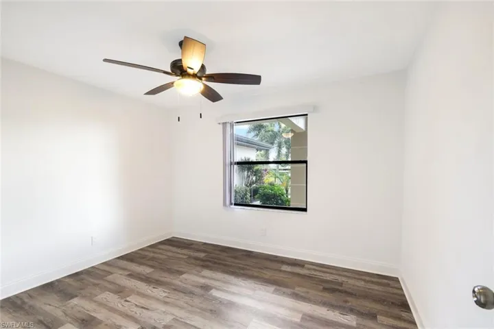 Empty room with dark wood-type flooring and a ceiling fan