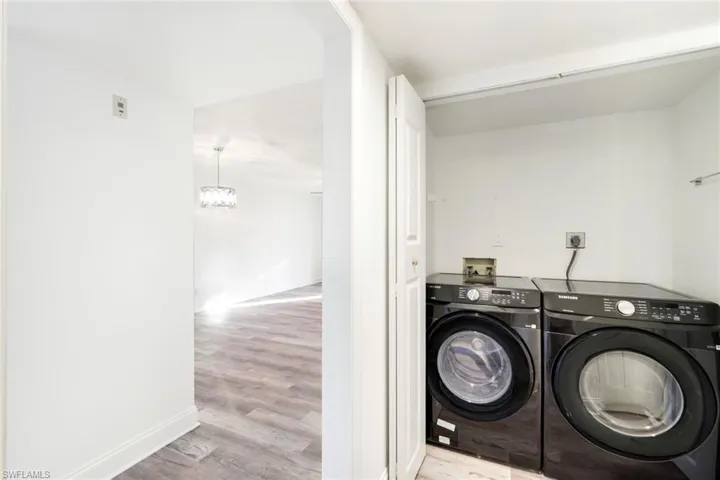 Washroom featuring light wood-style flooring, a chandelier, and separate washer and dryer