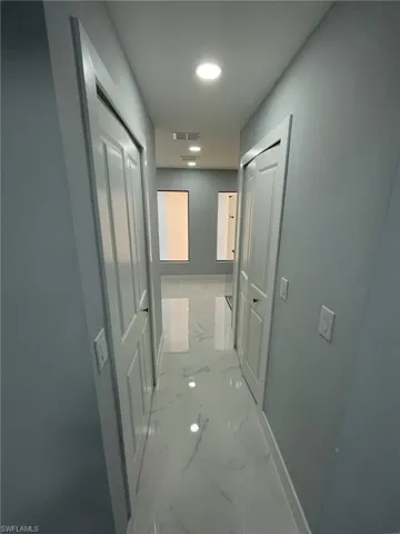 Corridor featuring light marble finish floors, baseboards, and recessed lighting