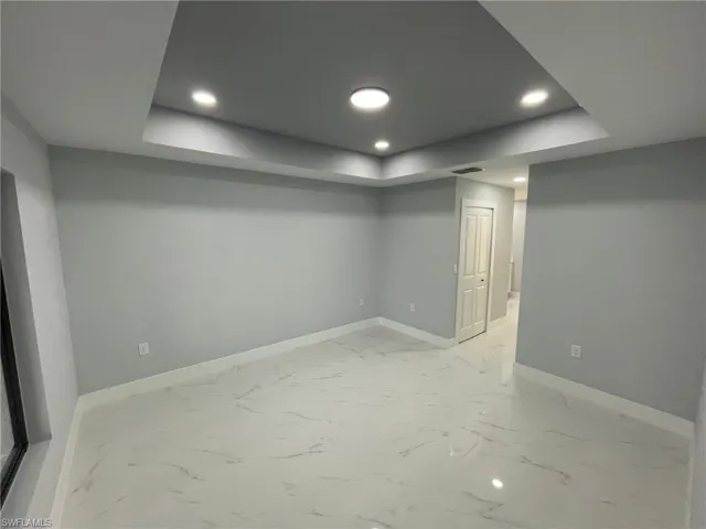 Finished below grade area with baseboards, recessed lighting, and light marble finish flooring