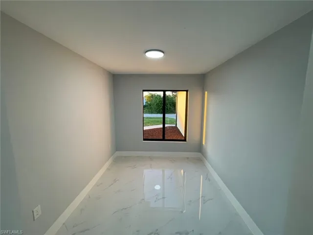Unfurnished room featuring light marble finish floors and baseboards