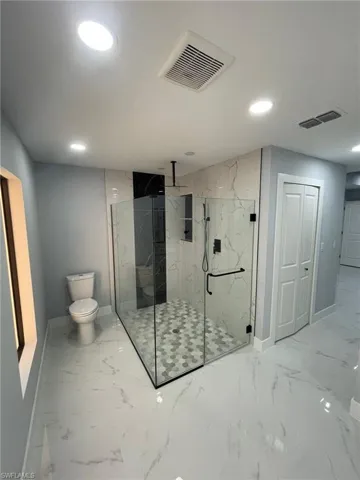 Full bath featuring baseboards, toilet, recessed lighting, marble finish flooring, and a marble finish shower