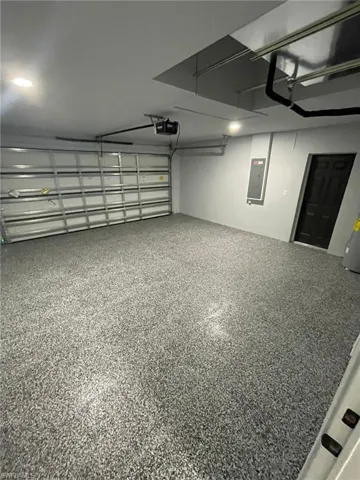 Garage featuring a garage door opener and electric panel