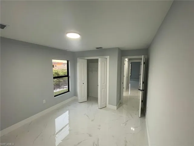 Unfurnished bedroom with baseboards, light marble finish flooring, and a closet