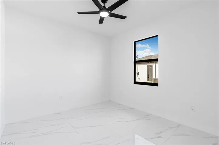 Spare room with light marble finish floors and ceiling fan