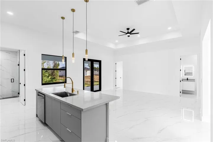 Kitchen featuring pendant lighting, gray cabinets, modern cabinets, light stone counters, and open floor plan