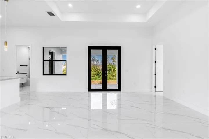 Unfurnished room featuring french doors, recessed lighting, a tray ceiling, and light marble finish flooring