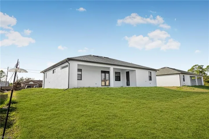 Back of property featuring stucco siding, a patio, and a lawn