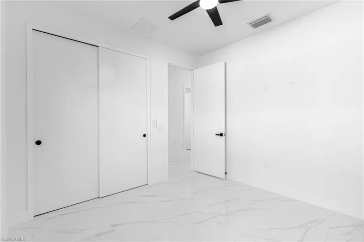 Unfurnished bedroom with marble finish flooring, a ceiling fan, and a closet