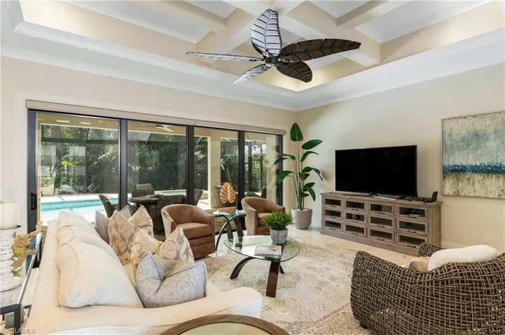 Living room featuring beamed ceiling, ceiling fan, coffered ceiling, and crown molding