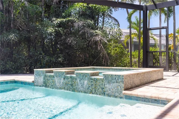 View of pool featuring a lanai, a pool with connected hot tub, and a patio area