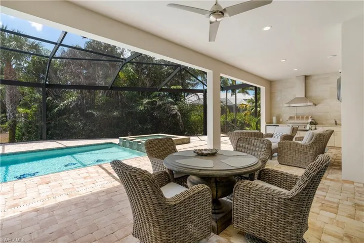 View of pool featuring a patio area, a pool with connected hot tub, an outdoor kitchen, a ceiling fan, and a grill