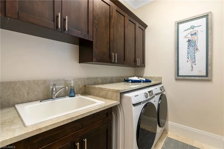 Laundry area with a sink, baseboards, cabinet space, and washing machine and dryer