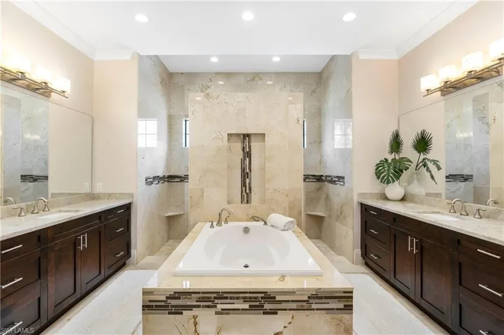 Full bath featuring ornamental molding, two vanities, and a sink
