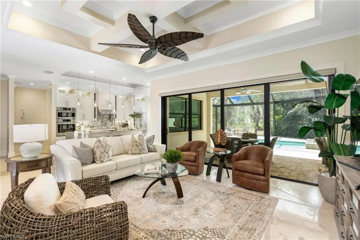 Living area with ornamental molding, coffered ceiling, marble finish floor, and ceiling fan