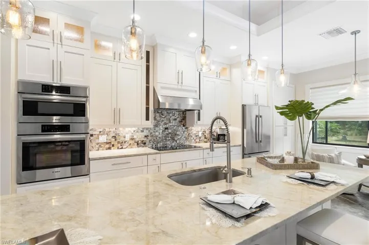 Kitchen with a sink, under cabinet range hood, visible vents, backsplash, and appliances with stainless steel finishes