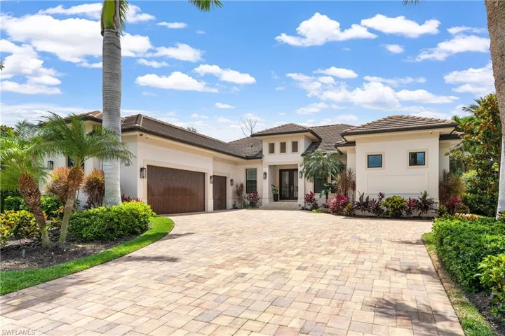 View of front facade featuring a garage, stucco siding, decorative driveway, and a tiled roof