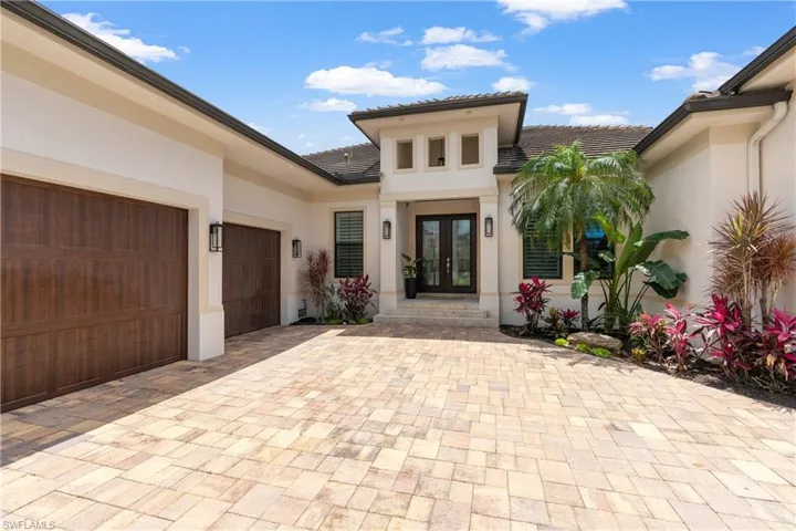 Doorway to property with stucco siding, decorative driveway, a tile roof, french doors, and an attached garage