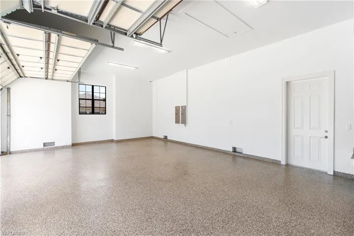 Garage with visible vents, electric panel, and baseboards