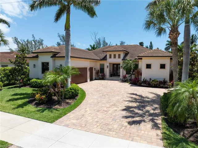 Mediterranean / spanish home with stucco siding, decorative driveway, a tiled roof, and an attached garage
