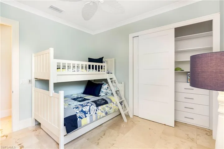 Bedroom with a closet, marble finish floor, visible vents, baseboards, and ornamental molding